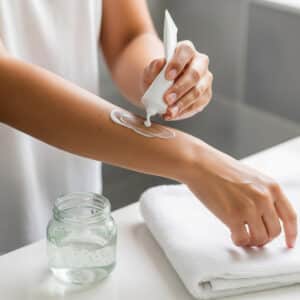 A person applies lotion to their arm after a hair removal session.
